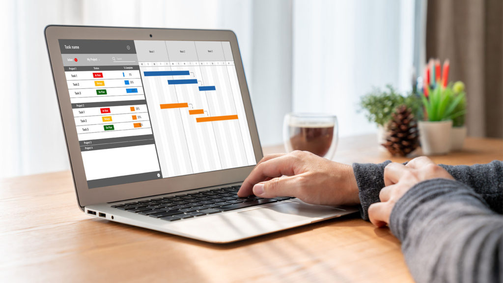 Como gerenciar projetos com software de gestão - homem em mesa de escritório com software de gestão em tela de notebook