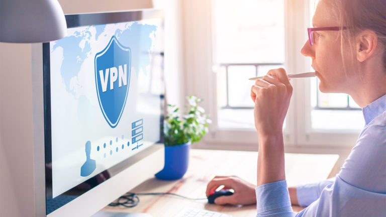 Quais os benefícios da VPN? Mulher em uma mesa de escritório em um computador apple acessando uma rede VNP.