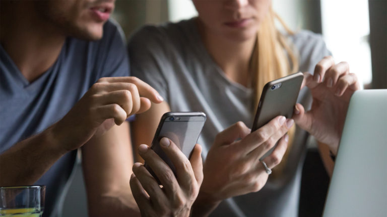 Serviços de tecnologia para empresas - Homem e mulher checando emails nos celulares