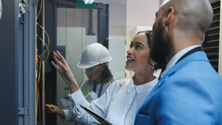 Mulher inspecionando um servidor firewall com equipe de suporte de TI