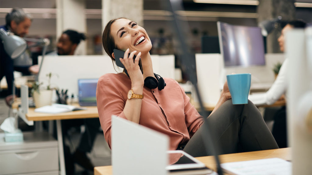 Mulher sorrindo no ambiente de trabalho após receber o atendimento humanizado em TI