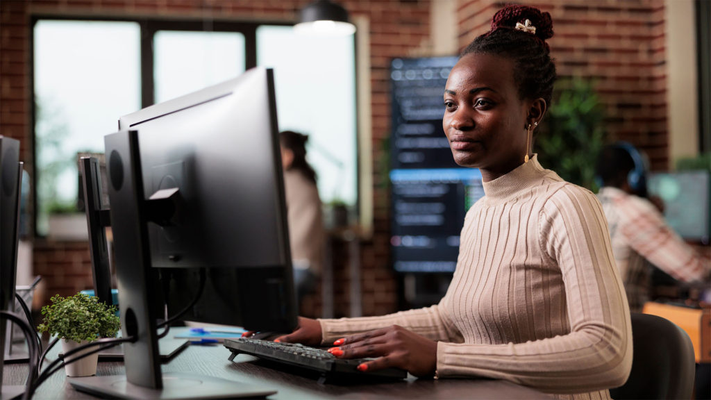 Mulher trabalhando em um computador com softwares atualizados e seguros