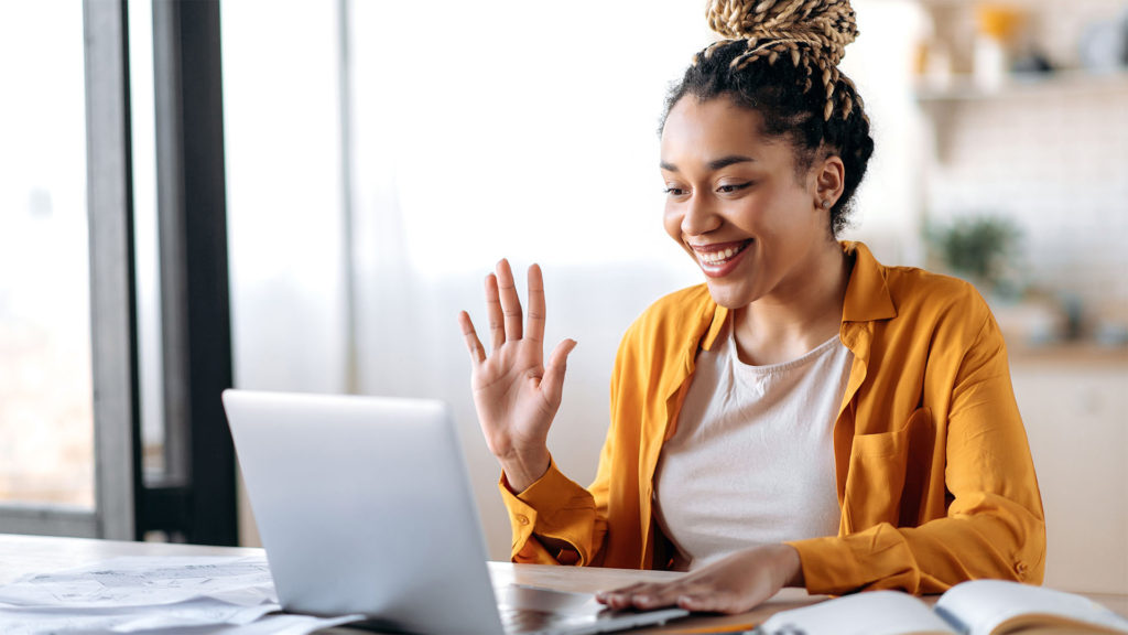 Mulher fazendo chamada de vídeo através de um notebook. Saiba as vantagens do trabalho remoto para os negócios