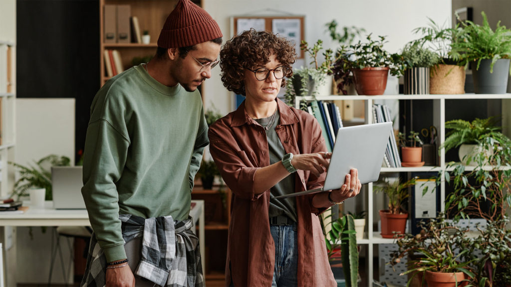 Dois colaboradores em frente a um notebook, sendo atendidos por suporte de TI