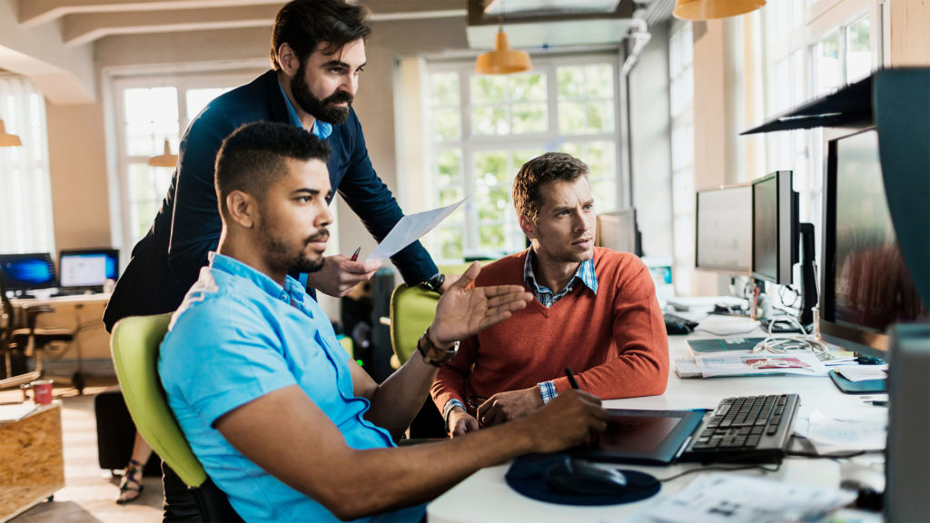 Dois homens e uma mulher em frente ao computador. Silos de dados é uma ameaça para produtividade